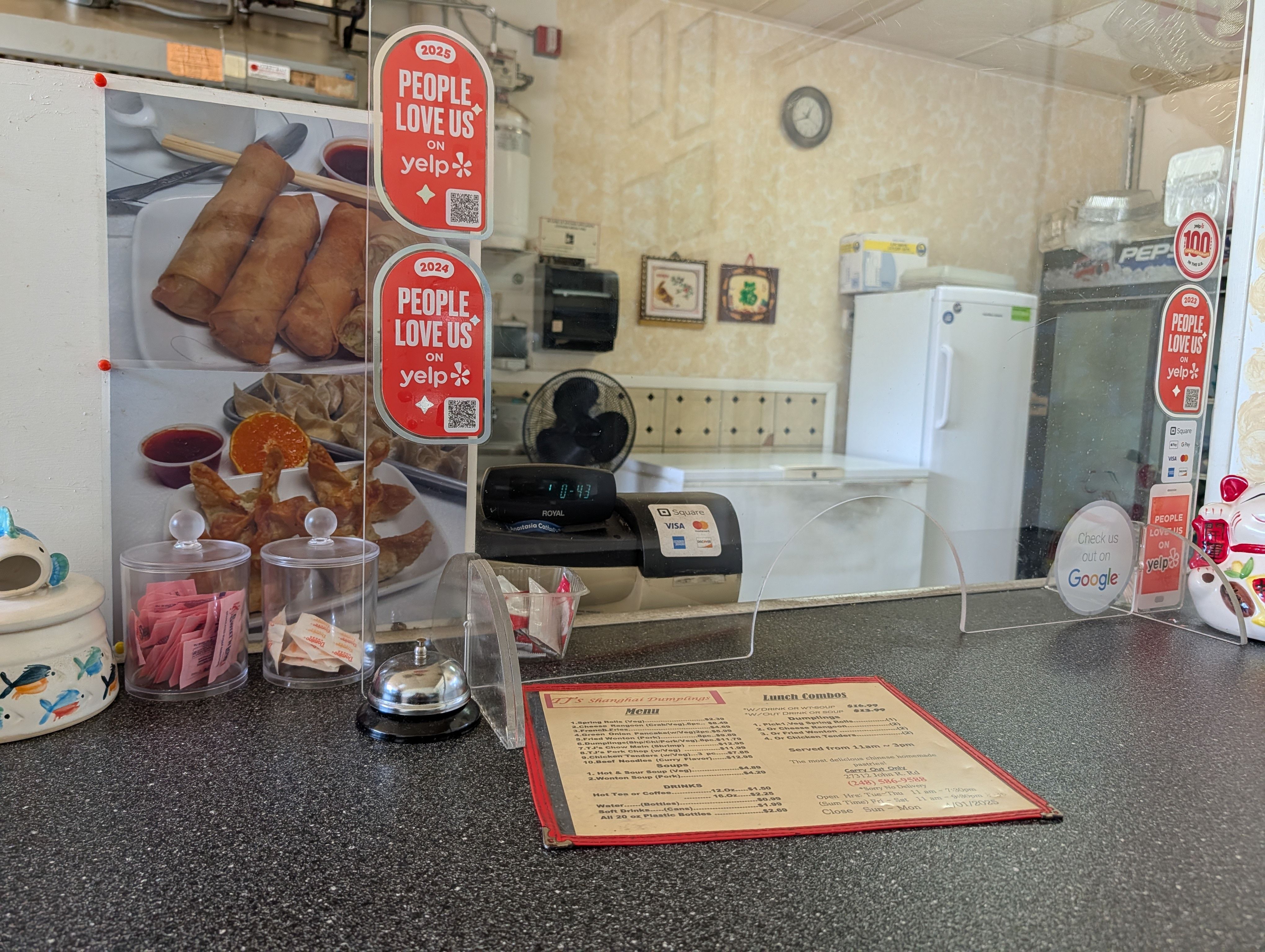 The order counter at TJ's with a laminated menu, register, and People Love Us on Yelp stickers
