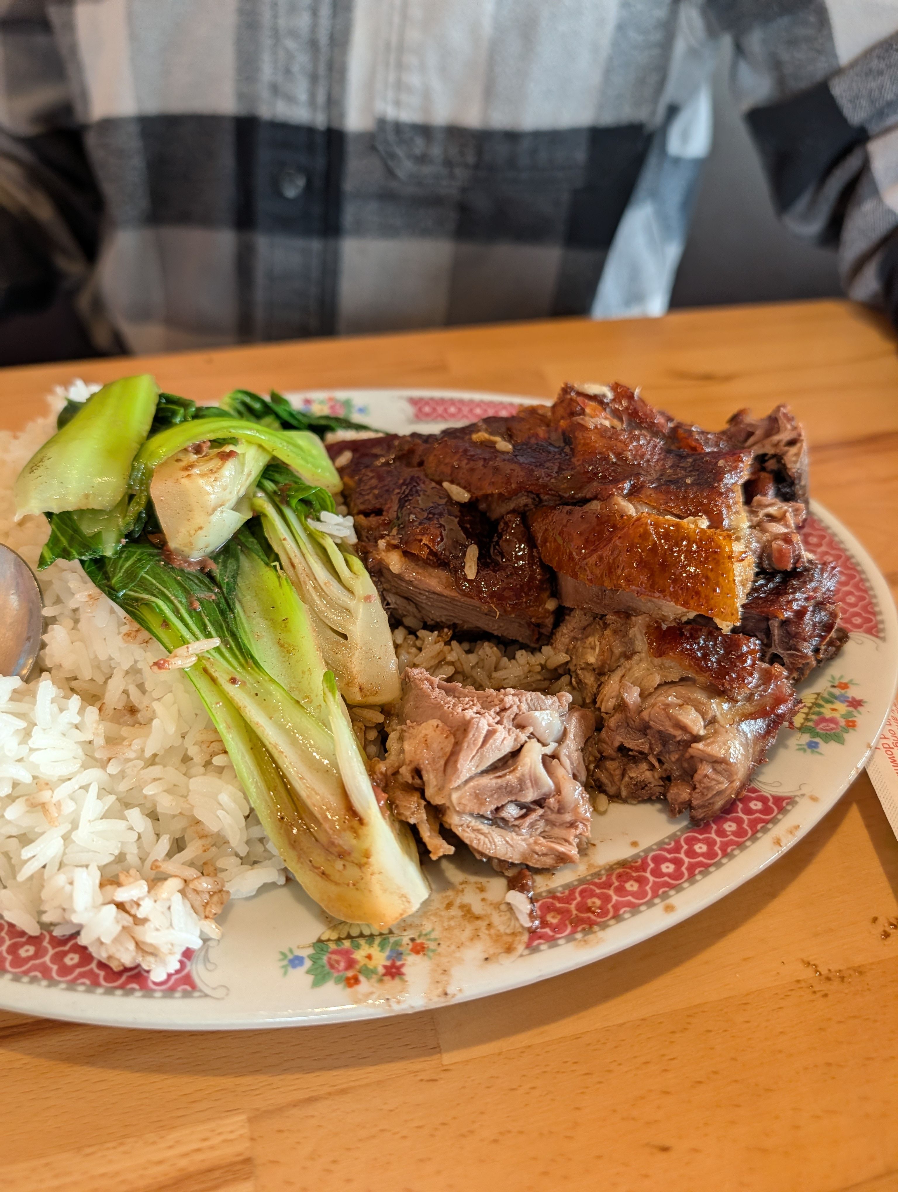 Cantonese roast duck over rice with baby bok choy on a floral-rimmed plate